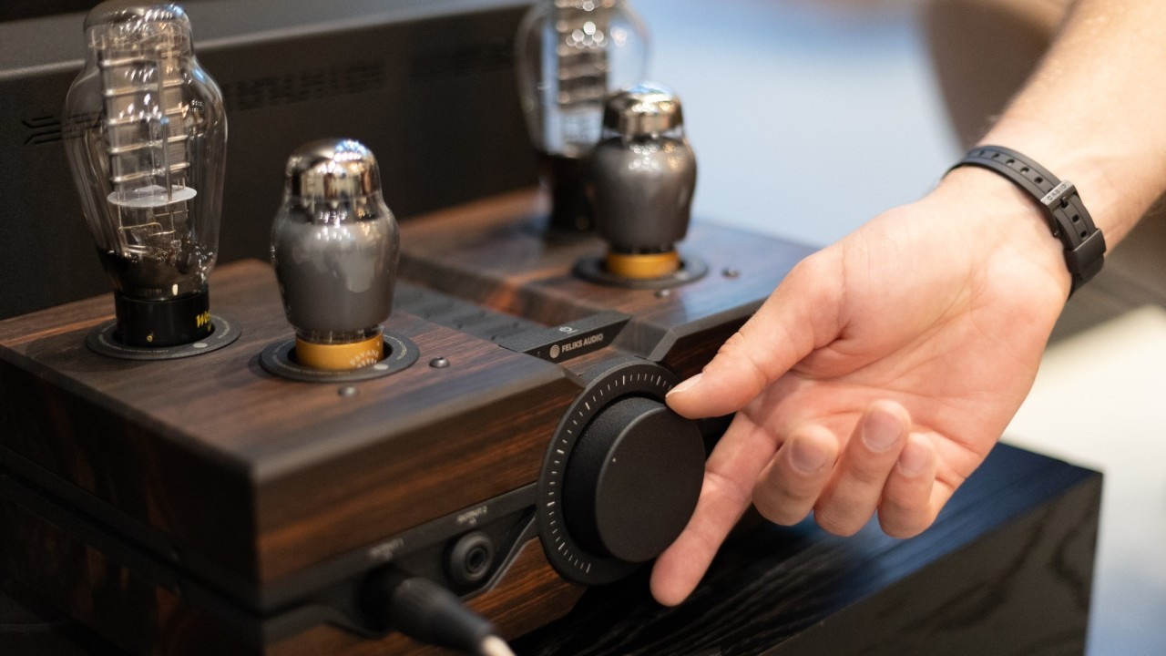 Person adjusting the volume using the knob on the Feliks Audio Envy tube amplifier.