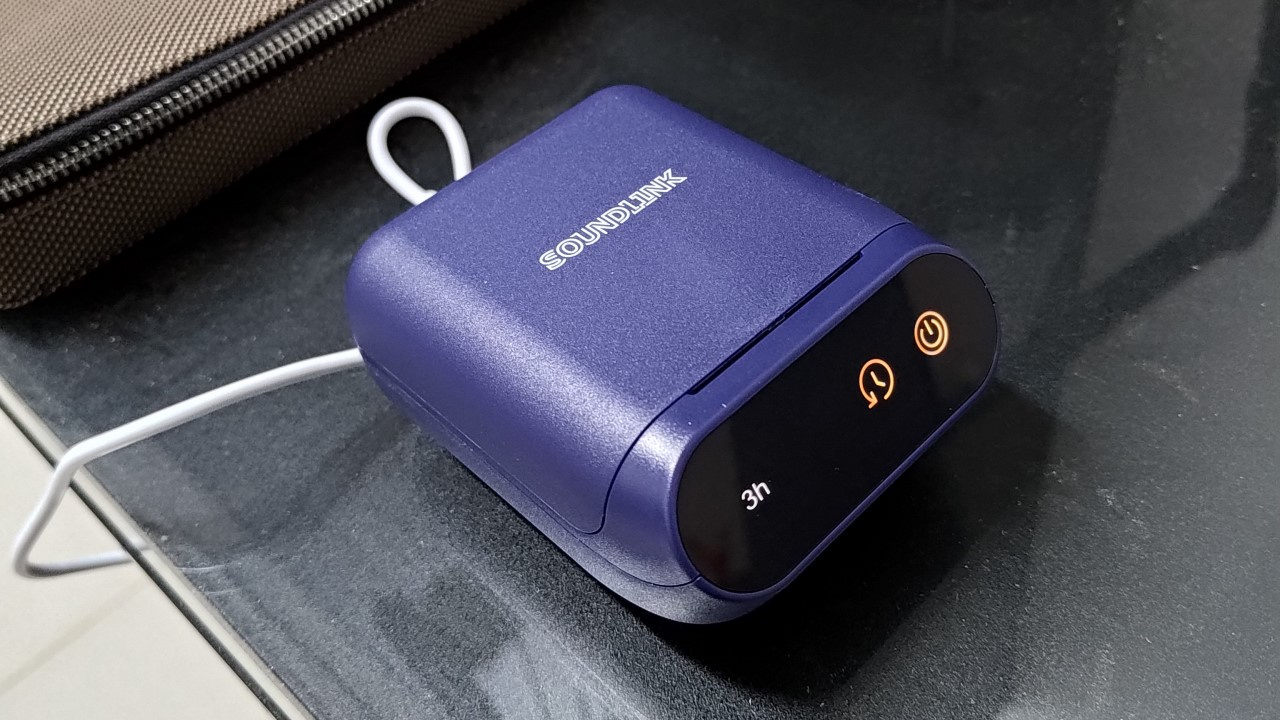 Foto do desumidificador elétrico SoundLink Aid 500 para aparelhos auditivos com bateria e fones de ouvido in-ear.