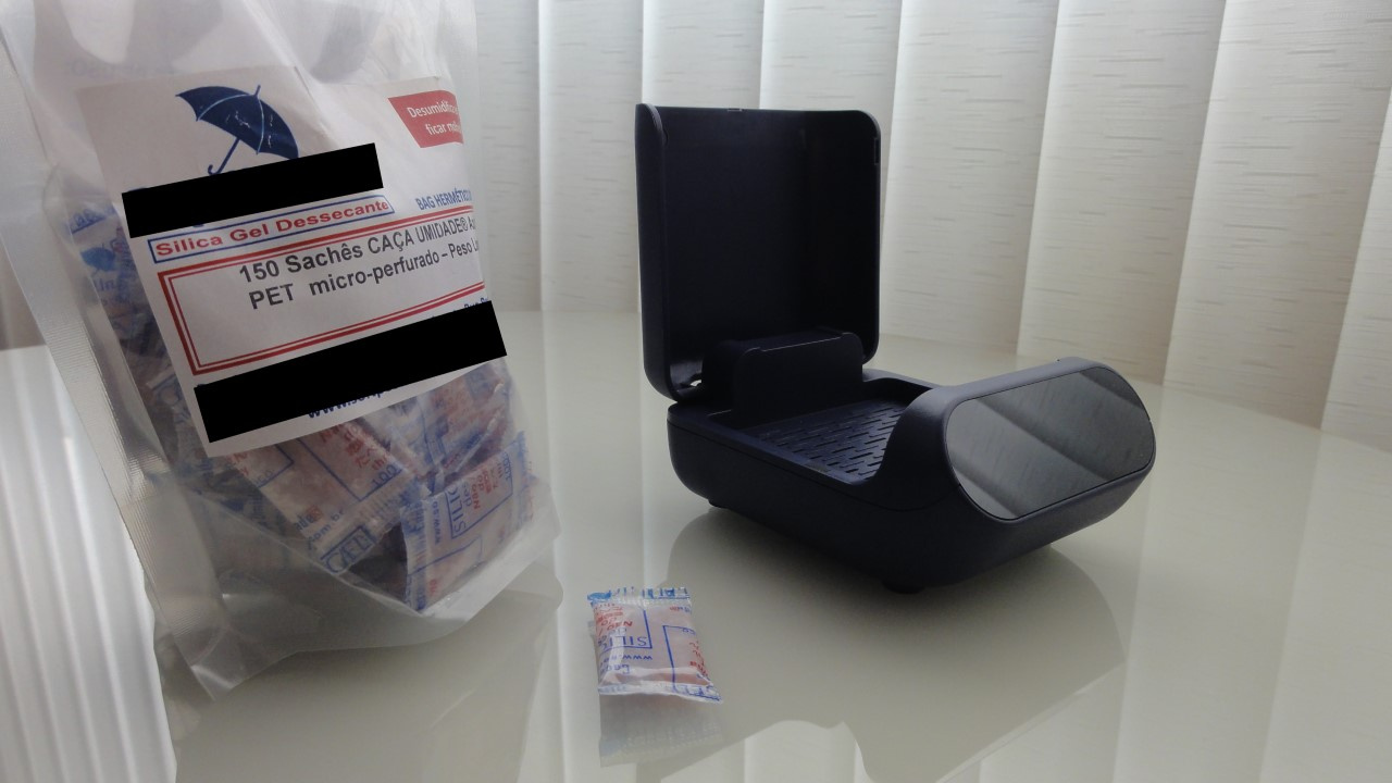 Pacote com saquinhos de silica e desumidificador elétrico de aparelhos auditivos.
